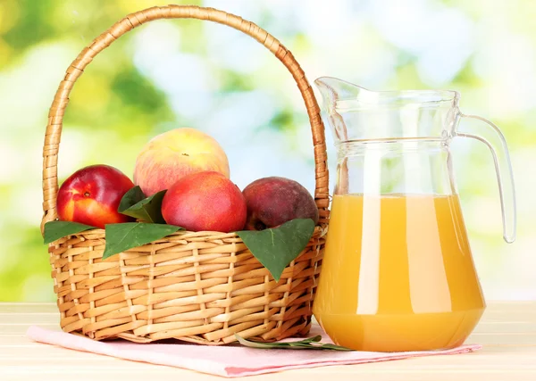 Спелые персики в корзине и сок на деревянном столе на естественном фоне — стоковое фото