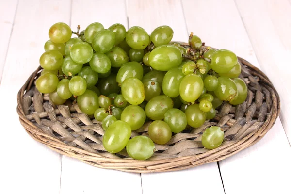 Uvas verdes maduras de cerca en cuna de mimbre sobre mesa de madera —  Fotos de Stock
