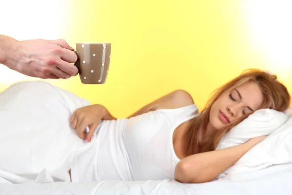 Sabah kahve Sarı zemin üzerine genç kadın yatakta — Stok fotoğraf
