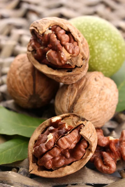 Walnuts with green leaves, on wicker background — Stock Photo, Image