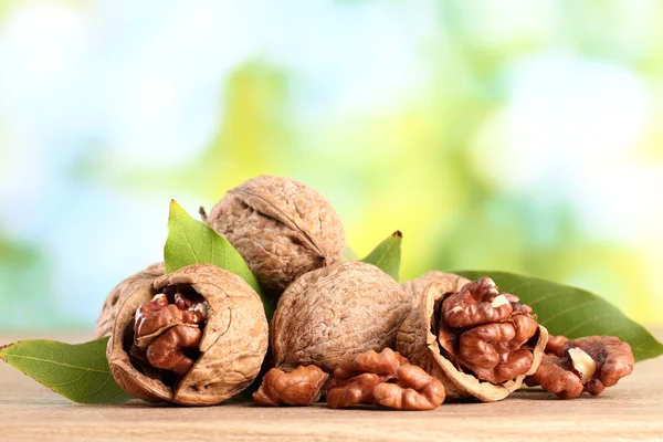 Valnötter med gröna blad, på grön bakgrund — Stockfoto