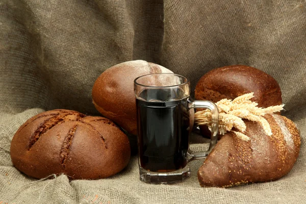 Korbel Kvas a žitné chleby s ušima, na pozadí pytlovina — Stock fotografie