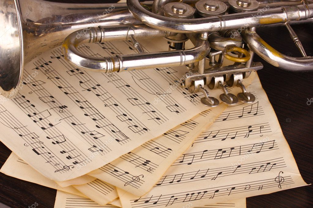 Musical notes and trumpet on wooden table Stock Photo by ©belchonock