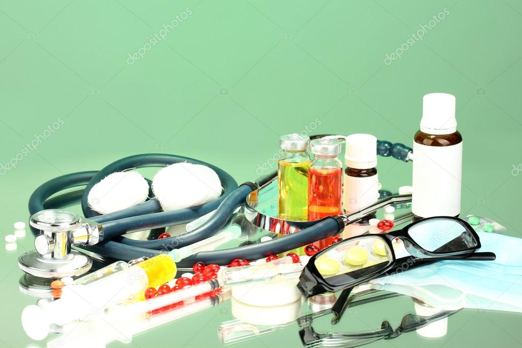 medicines and a stethoscope on a green background close-up