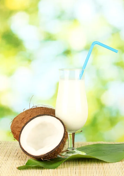 Glass of coconut milk and coconuts on green background close-up — Stock Photo, Image