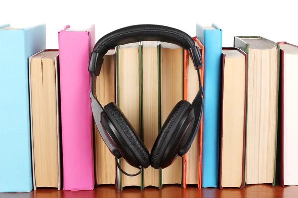 Auriculares en libros sobre mesa de madera sobre fondo blanco — Foto de Stock