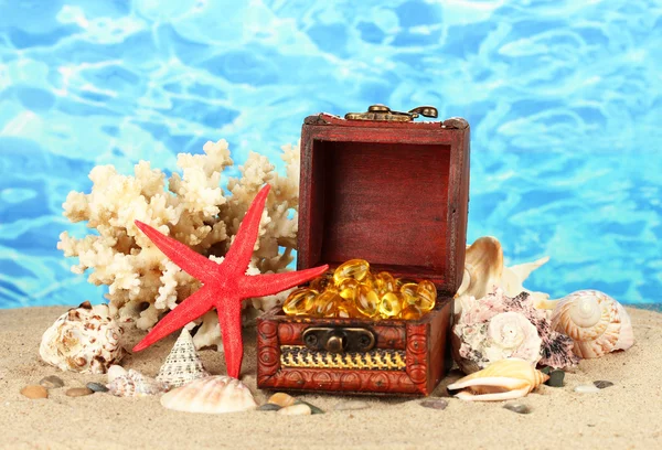 Olej z ryb w klatce piersiowej na piasku na niebieskim tle z bliska — Zdjęcie stockowe