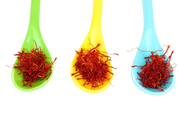 Stigmas of saffron in multicolored spoons on white background close-up — Stock Photo, Image