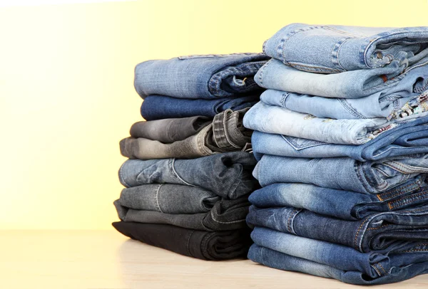 Mange jeans stablet i en bunker på gul baggrund - Stock-foto