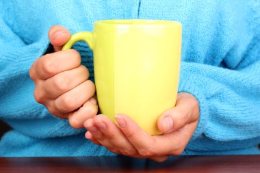 yakın çekim sıcak bir fincan tutan eller iç