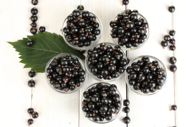 Fresh black currant in transparent bowls on white wooden background close-u — Stock Photo, Image