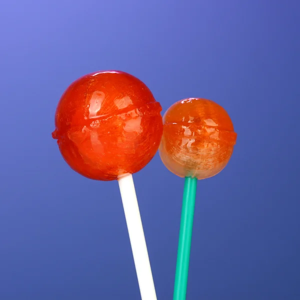 Lollipops brilhantes e deliciosos no fundo azul escuro close-up — Fotografia de Stock