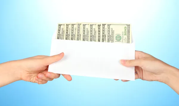 Woman's hand passes the envelope with the salary on blue background — Stock Photo, Image