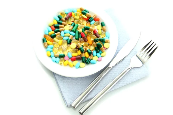 Colorful capsules and pills on plate with fork and knife, isolated on white — Stock Photo, Image