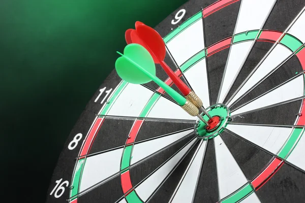 Dart board with darts on green background — Stock Photo, Image