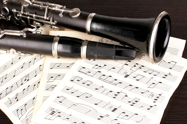 Notas musicais e clarinete na mesa de madeira — Fotografia de Stock