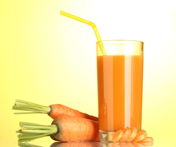 Vidro de suco de cenoura no fundo amarelo — Fotografia de Stock