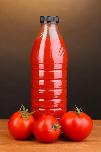 Jus de tomate en bouteille sur table en bois sur fond brun — Photo