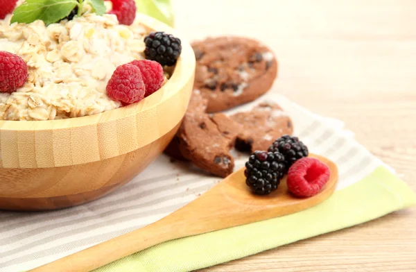 Tasty oatmeal with berries, on wooden table — Stock Photo, Image