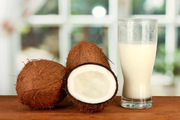 Vaso de leche de coco y cocos en la mesa de madera de cerca —  Fotos de Stock