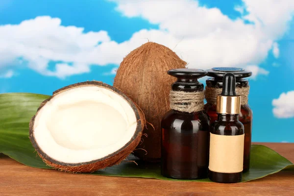 Aceite de coco en botellas con coco en el fondo del cielo —  Fotos de Stock