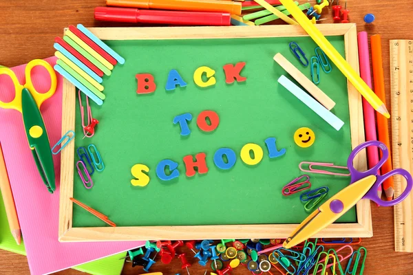 Small chalkboard with school supplies on wooden background. Back to School — Stock Photo, Image