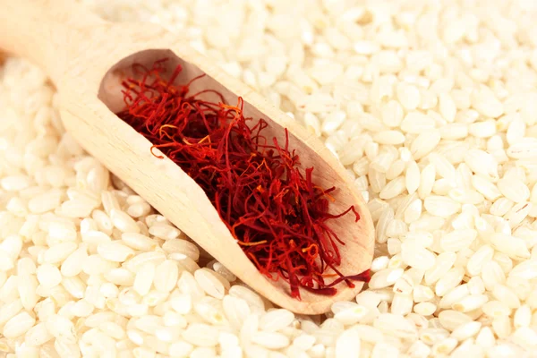 Estigmas de azafrán en cuchara de madera sobre arroz de cerca — Foto de Stock