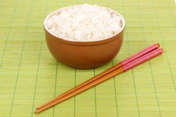 Tigela de arroz e pauzinhos em esteira de bambu — Fotografia de Stock