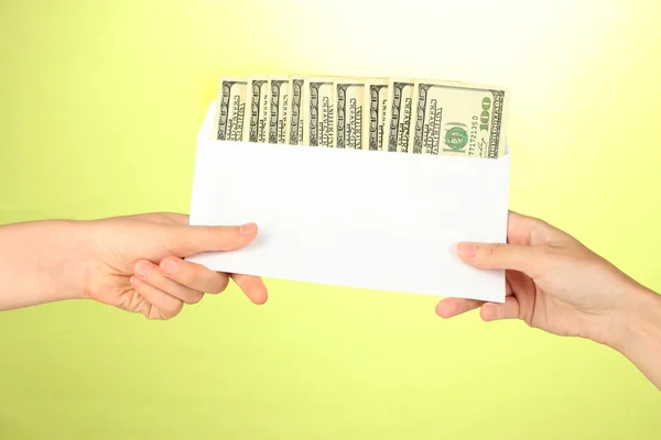 Woman's hand passes the envelope with the salary on green background — Stock Photo, Image