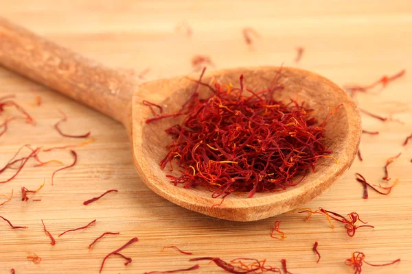 Stigmas of saffron in wooden spoon on wooden background close-up — Stock Photo, Image