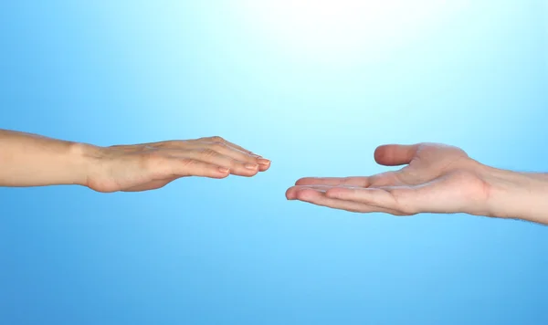 Women's hand goes to the man's hand on blue background Stock Picture