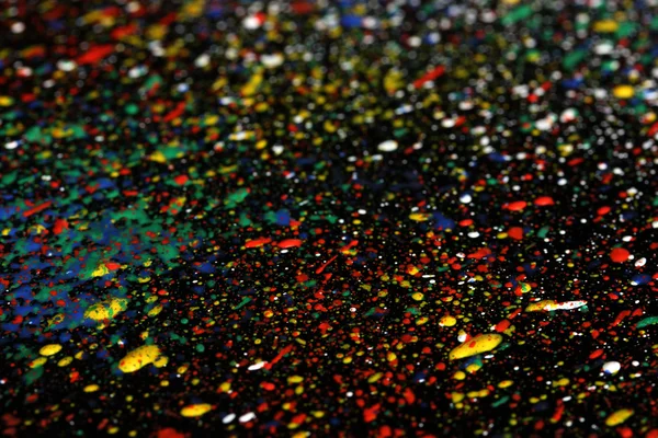Bright splashes of paint on black background close-up — Stock Photo, Image