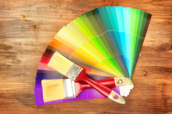 Paint brushes and bright palette of colors on wooden background — Stock Photo, Image