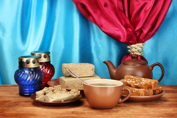 Чайник с чашкой и блюдцами с восточными сладостями - шербет и халва на woo — стоковое фото