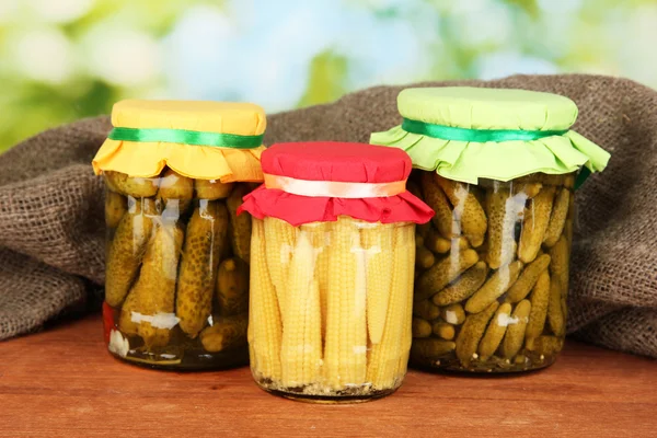 Frascos con verduras enlatadas sobre fondo verde de cerca — Foto de Stock