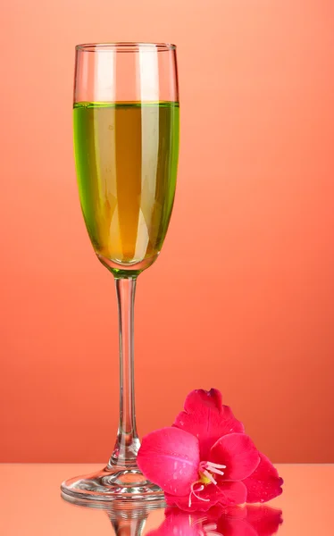 Glass with cocktail and gladiolus bud on red background close-up — Stock Photo, Image