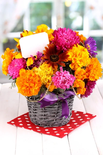 Beautiful bouquet of bright flowers with paper note on wooden table on wind — Stock Photo, Image