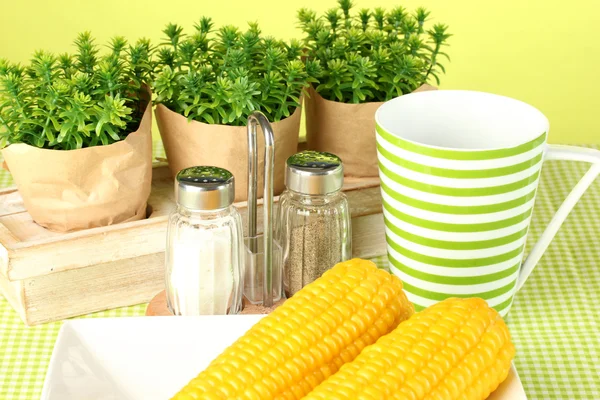 Boiled corn and flowers on a green background — Stock Photo, Image