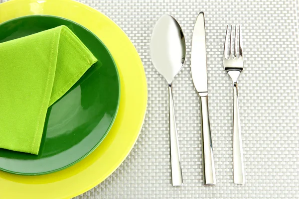 Green empty plates with fork, spoon and knife on a grey tablecloth — Stock Photo, Image