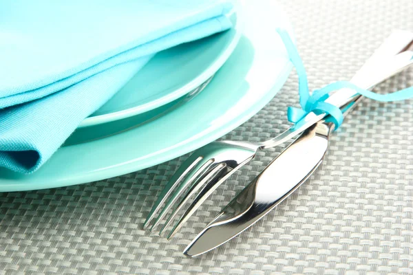 Голубые пустые тарелки с вилкой и ножом на серой скатерти — стоковое фото