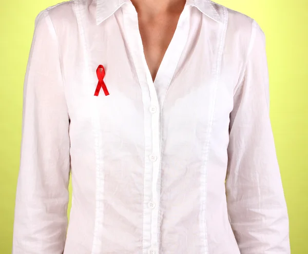 Woman with red ribbon on white shirt on green background — Stock Photo, Image