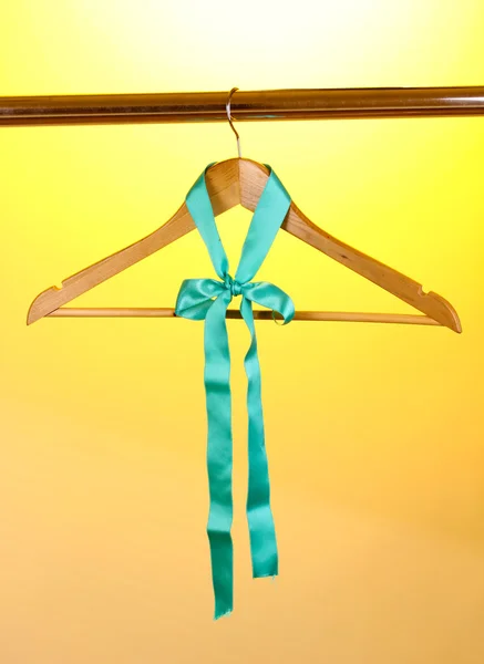 Prachtige turquoise boog opknoping op houten hanger op gele achtergrond — Stockfoto
