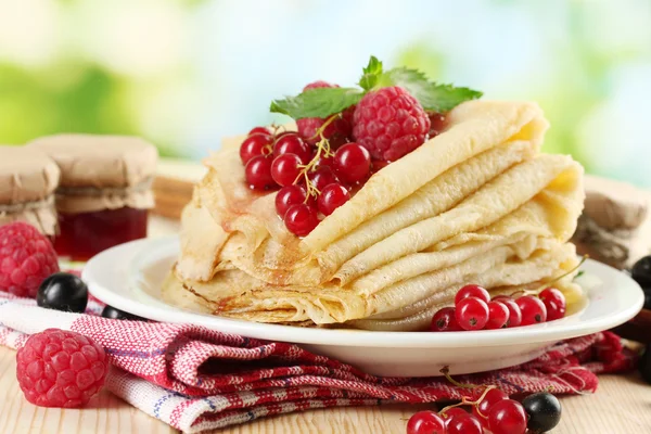 Tortitas con bayas, mermelada y miel sobre mesa de madera sobre fondo verde — Foto de Stock