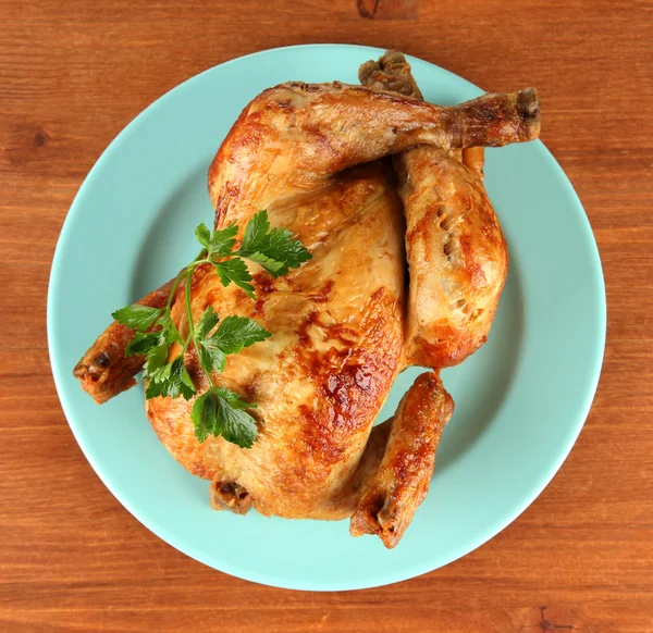 Poulet entier rôti sur une assiette bleue sur fond de bois — Photo