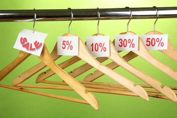 Cabides de roupas de madeira como símbolo de venda no fundo verde — Fotografia de Stock