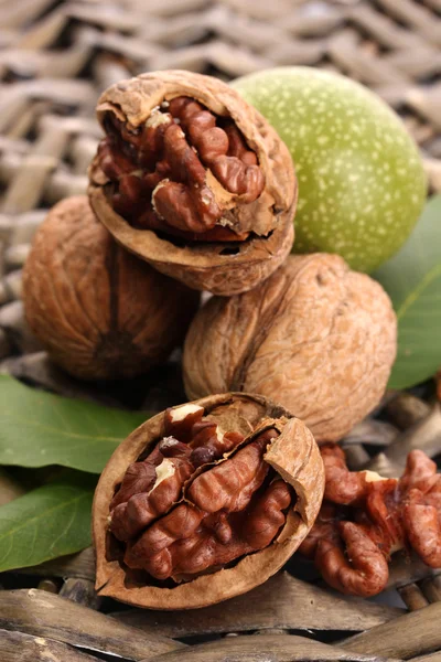 Walnuts with green leaves, on wicker background — Stock Photo, Image