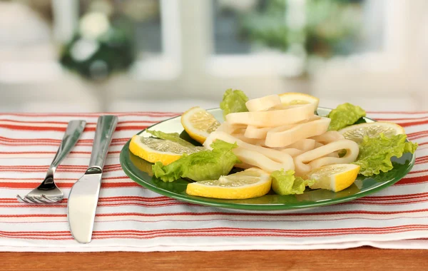 Anillos de calamar cocidos en lechuga con limón en el primer plano del plato — Foto de Stock