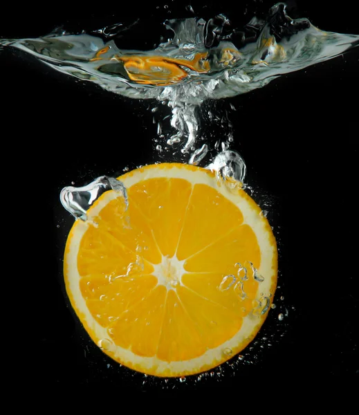 Fatia de laranja na água sobre fundo preto — Fotografia de Stock