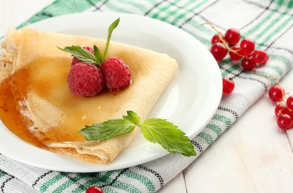 Panqueca deliciosa com bagas e mel no prato na mesa de madeira — Fotografia de Stock