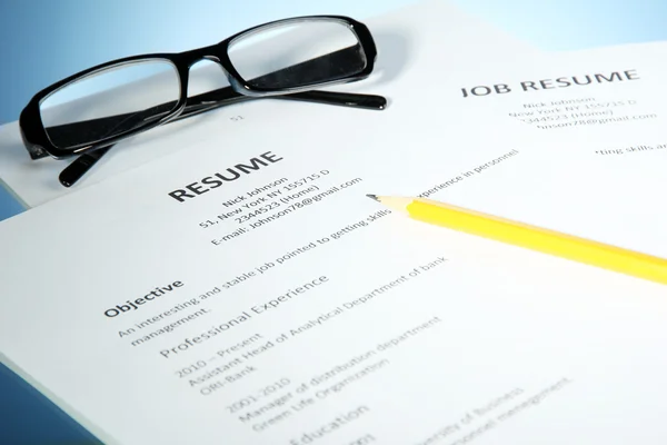 Closeup of resume with glasses and pencil on blue background — Stock Photo, Image